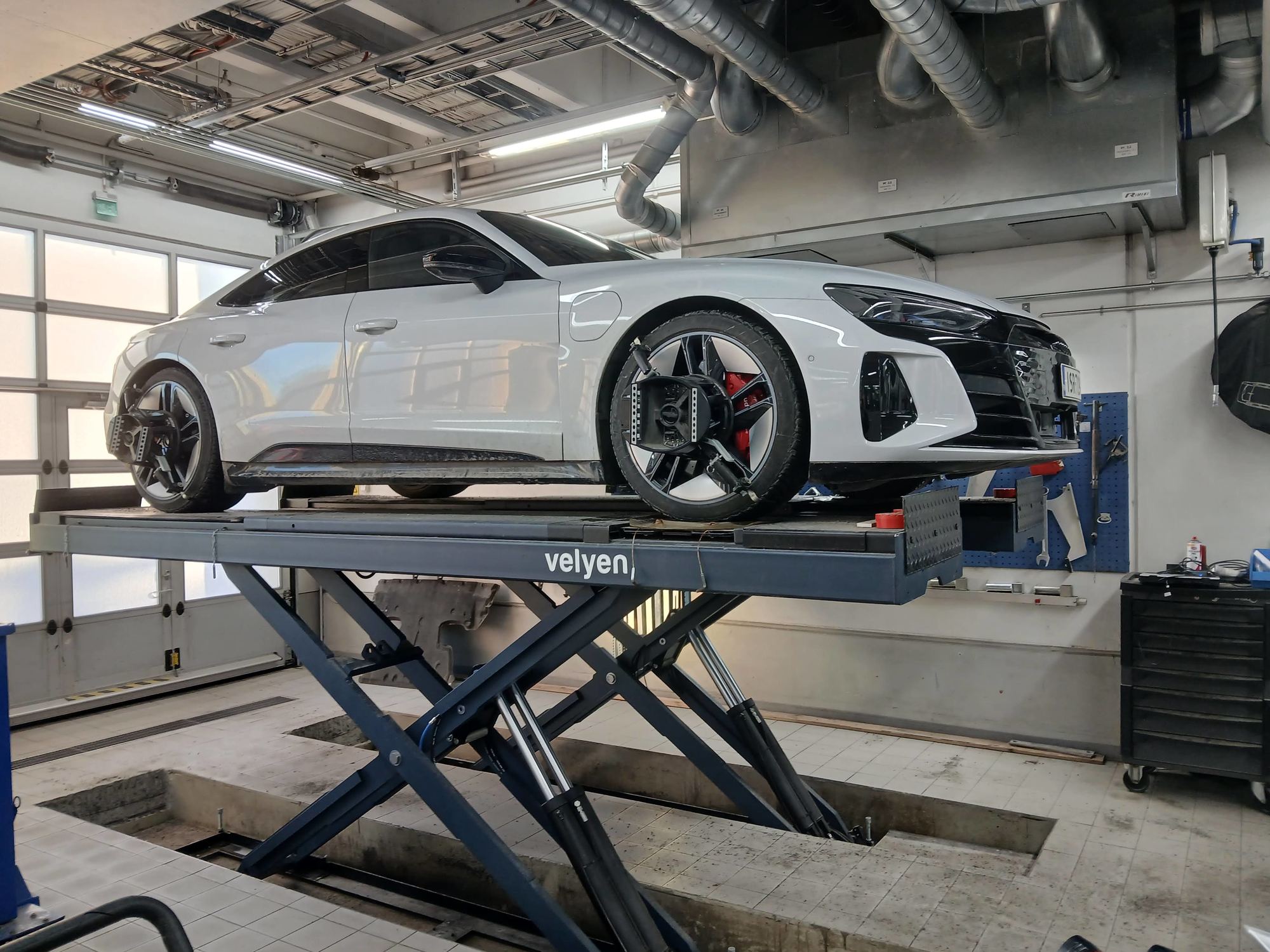 Henkilöauto saksinostimella valoisassa korjaamohallissa