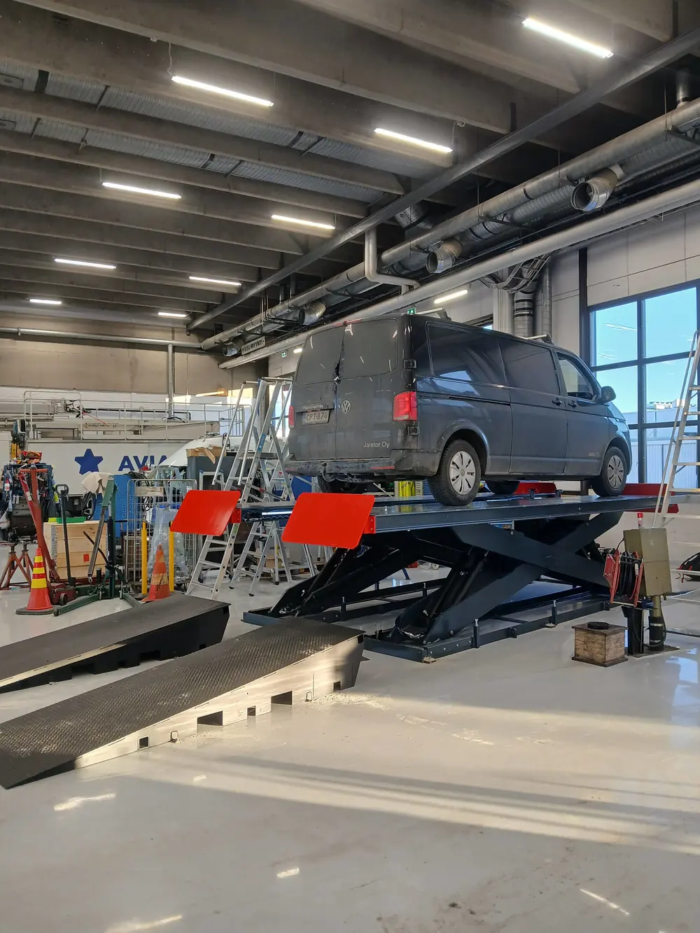 Jalator Oy:n pakettiauto nostimella korjaamohallissa